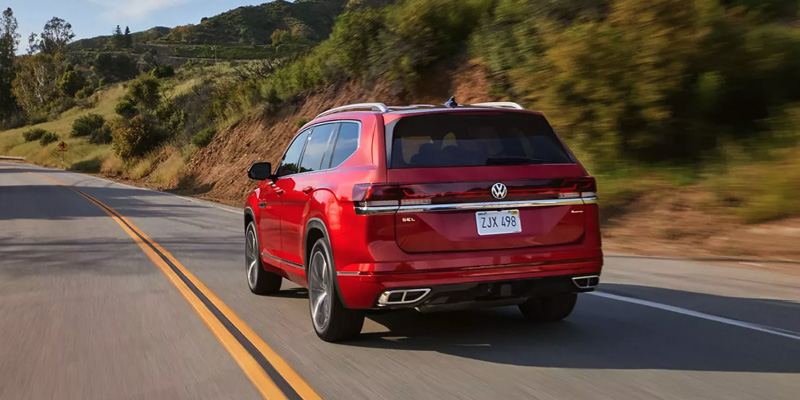 A red Volkswagen SUV driving on a scenic road