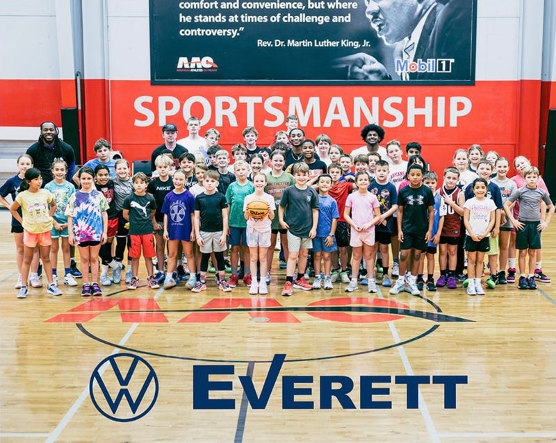 A large group of children and several adults on a basketball court, with Sportsmanship and a MLK quote on the wall